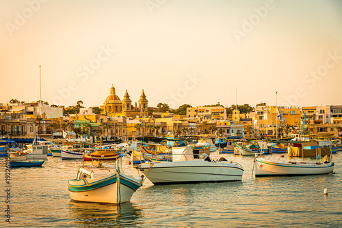 Boats in the port of Marsaxlokk with the Church of Our Lady of Pompeii in the background. Malta.