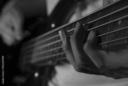 Foto Close up of musician playing electric bass guitar in black and white