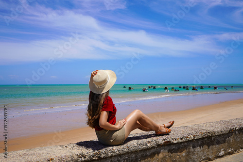 Traveler woman enjoying panoramic view of natural swimming pools with jangadas rafts in Joao Pessoa, Brazil