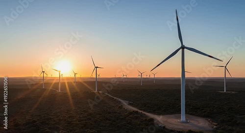 Wind turbines at sunset with golden light across a vast landscape generating renewable energy with turning blades against a scenic sky