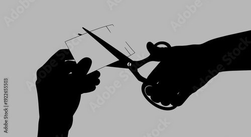 Hand holding paper being cut by scissors in silhouette against a gray background viewpoint