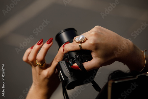 Woman's hands taking a photo with a digital camera, red nails, skin texture, rear view close-up, at Wat Arun.