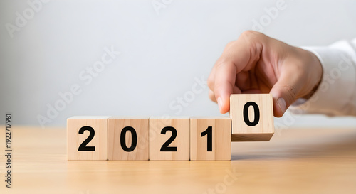 Hand changing wooden blocks to turn 2021 into 2020 for new year concept planning strategy