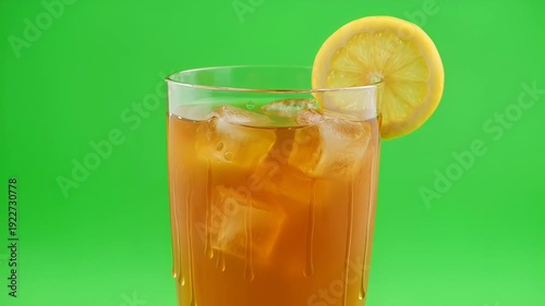 refreshing glass of iced tea with lemon slice on vibrant green background