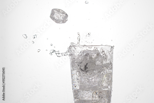 Ice splashes into glass of water.