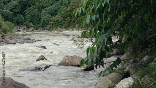 Powerful Turbulent Brown River Current Cascading Over Rapids and Rocks