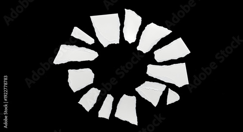 Torn white paper fragments arranged in circular pattern on black background for graphic design project