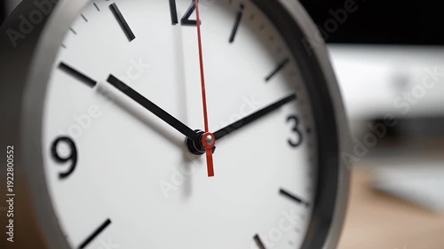 Closeup of a white clock face with black hour and minute hands and a red second hand
