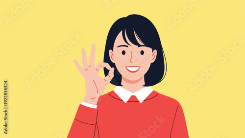 Smiling young woman making an okay hand gesture wearing a red sweater against a bright yellow background conveying positivity and success.