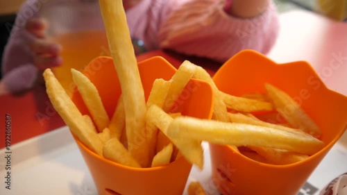 Closeup family picking up eating French fries potato chips in fast food restaurant