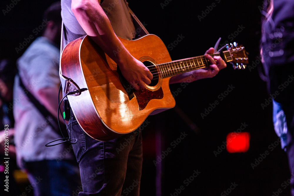 Fototapeta premium Musician playing acoustic guitar on stage during live concert