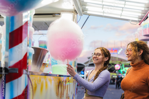 Принти на полотні Two happy friends at a fair buying pink cotton candy, sharing joyful moment
