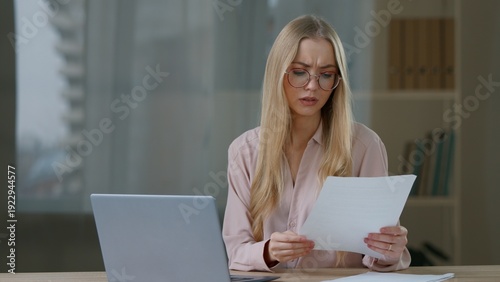 Billede på lærred Caucasian business woman with laptop working confused checking paper documents m