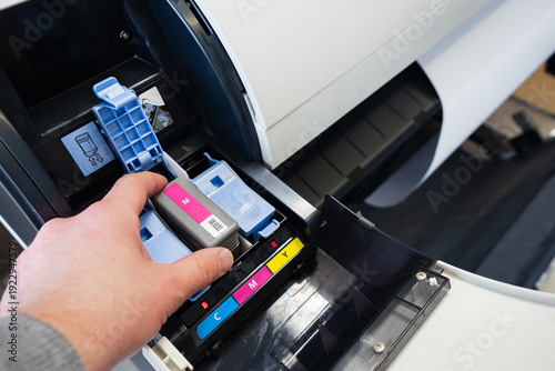 Tableau sur toile Close-up of a worker's hand changing the magenta ink cartridge inside a professi