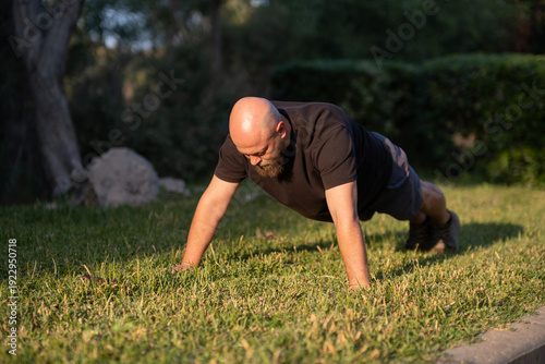 Fotografie Man Doing Push Ups on Grass in Park