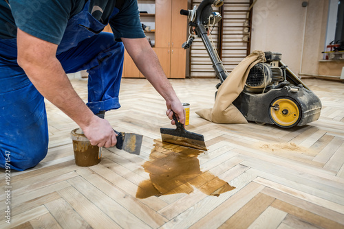 фотографія Professional worker fills the gaps cracks of the old wooden parquet with a spatula after sanding
