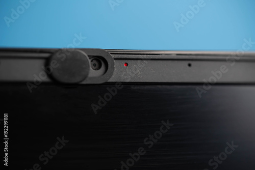Laptop webcam with red indicator light on, symbol of online surveillance, privacy risk and cyber security awareness concept.