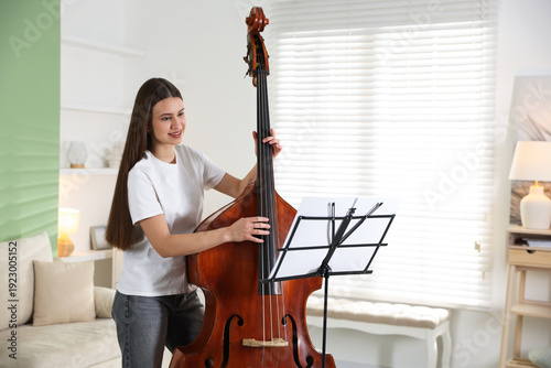Bild auf Leinwand Teenage girl playing double bass at home