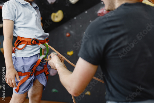 Fotografie Midsection of a girl at climbing wall with male instructor in climbing center