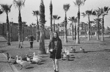 35 mm B&W film photo of woman with coat in city park by ducks
