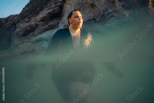 Man Wades Through Shallow Water Near Rocky Coastline at Sunset