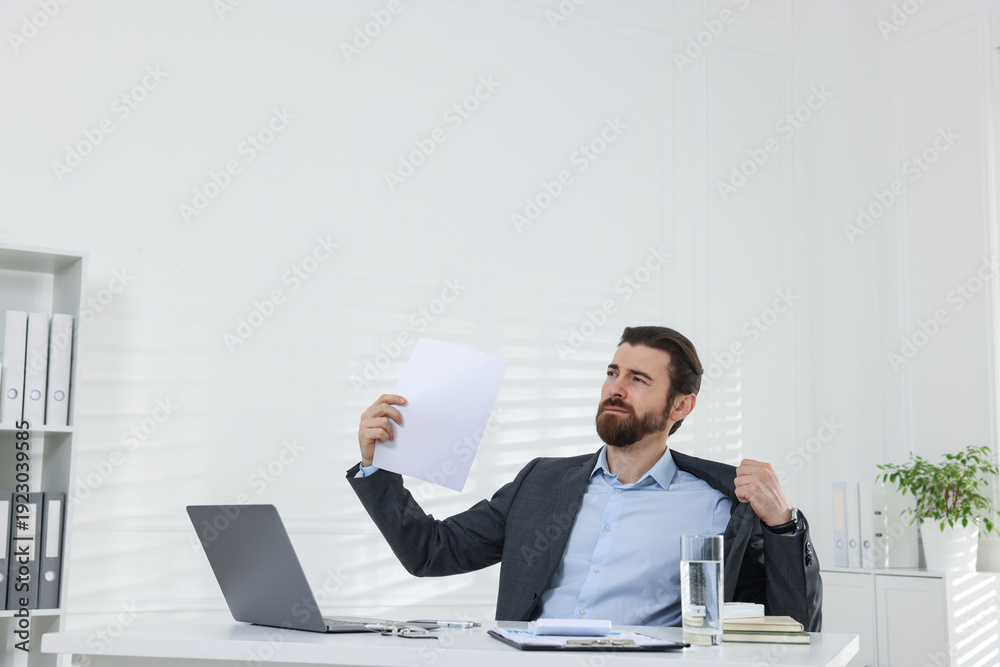 Fototapeta premium Man suffering from heat at table near white wall indoors, space for text