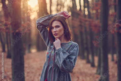 Portrait of young woman in autumn forest at sunset