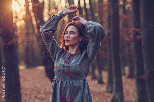 Young woman enjoying autumn nature with raised hands