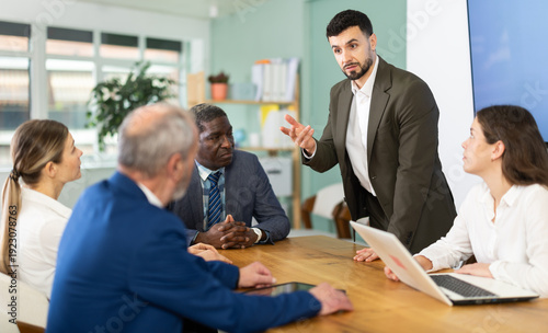 Fotografia Man stands in front of business colleagues, tells report, proves vision of situation, defends way to solve problems
