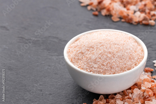 Himalayan pink salt in a white bowl on a minimalist dark background.