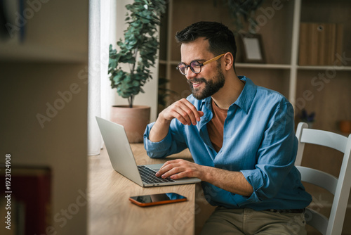 Canvas-taulu Man working from home on laptop, telecommuting smiling