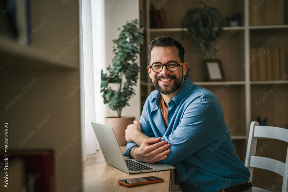 Fototapeta premium Man smiling working from home office on laptop