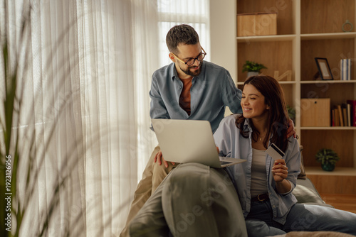 Young happy couple shopping online using laptop and credit card