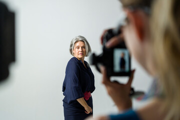 Photographer taking photos of beautiful mature model in studio