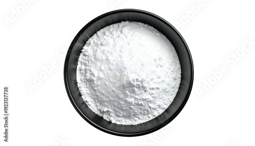 Overhead shot of white, powdery substance filling a black, round bowl, isolated on black