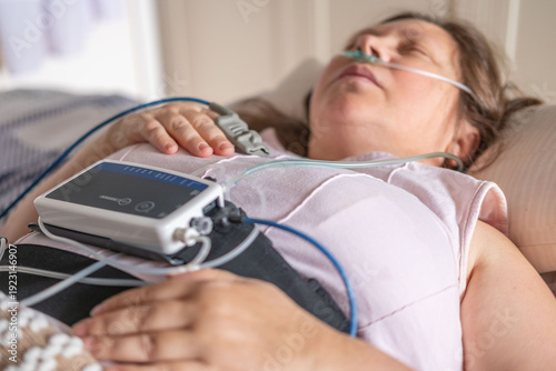 Bild auf Leinwand Woman resting in bed with home medical monitoring device, nasal cannula oxygen,