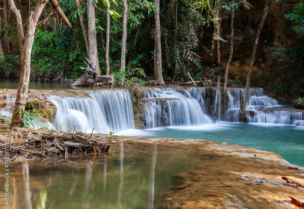 Obraz premium Huay Mae Khamin Waterfalls cascading through lush forest in Sri Nakarin Dam National Park, Thailand. Green trees and rocks frame flowing streams. Tropical jungle landscape with fresh water.