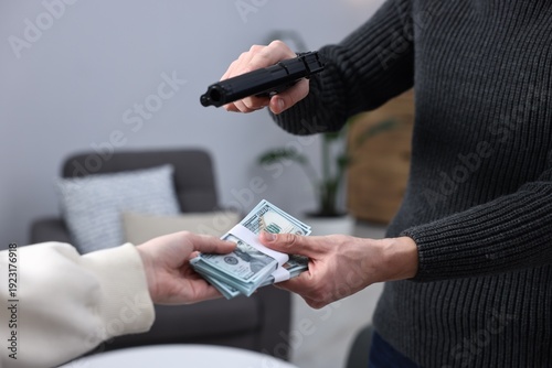Fényképezés Woman giving money to dangerous criminal with gun indoors, closeup
