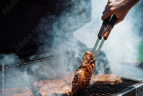 Fotografi Grilling juicy beef steaks on outdoor BBQ with smoke