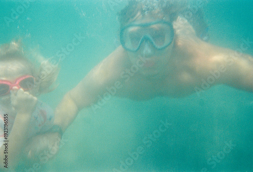 Child and Adult Swimming Underwater in Clear Ocean Water