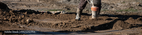 Photography Construction worker using a compactor rammer machine to manually pack the fresh