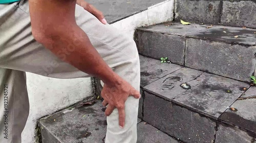 A man on the stairs holding his sore calf.