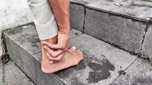 A man climbs the stairs holding his sore ankle.