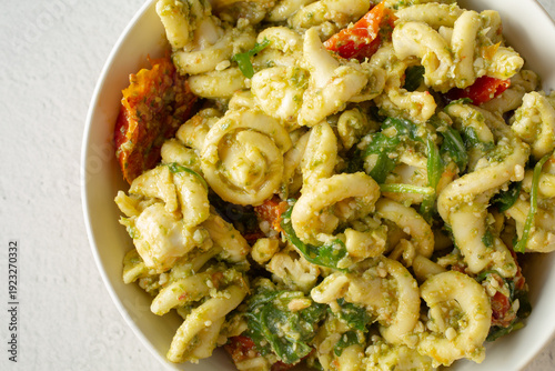 A top down view of a bowl of trottole pesto pasta salad.
