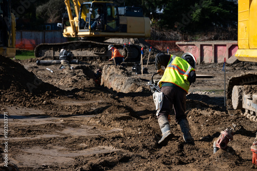 Foto Construction worker using a compactor rammer machine to manually pack the fresh