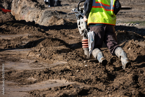 Foto Construction worker using a compactor rammer machine to manually pack the fresh