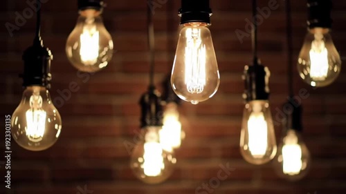 A group of vintage style light bulbs are hanging against a brick wall background, creating a warm and inviting