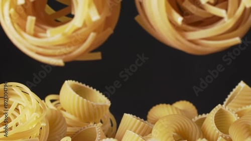 Various types of uncooked pasta are arranged against a dark background, creating a visually appealing composition.