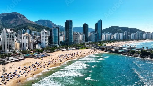 Aerial view of a vibrant city beach with mountains and buildings