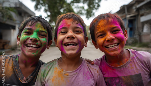 Three laughing boys with faces covered in vibrant Holi powder, sharing a moment of pure joy and celebration in an outdoor setting.